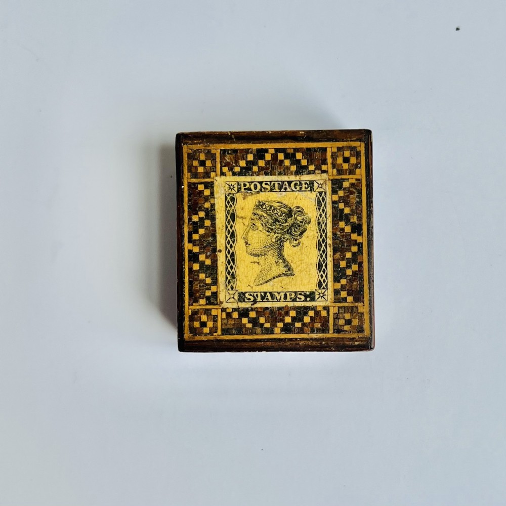 A small square antique wooden Tunbridge Ware stamp box featuring a central Queen Victoria postage stamp motif framed by a tessellated geometric wood inlay border.