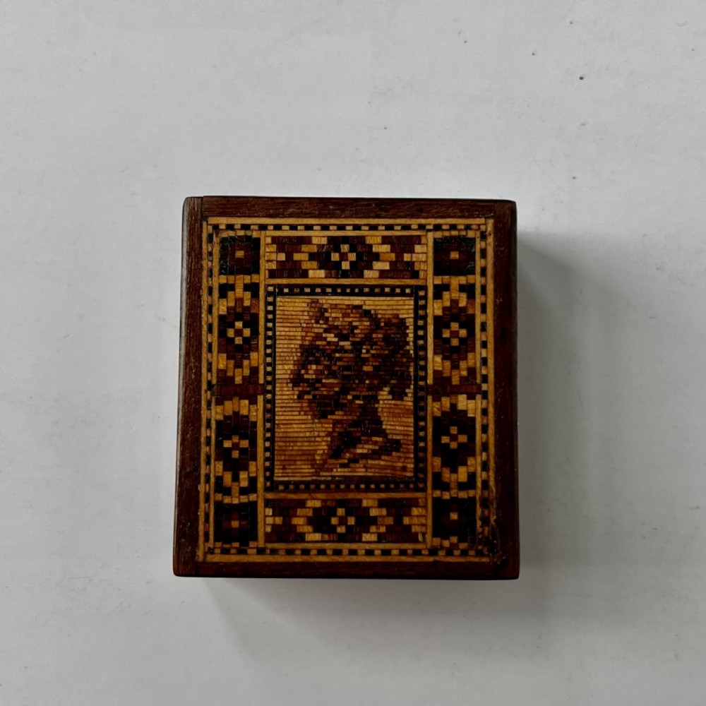 A small square Victorian Tunbridge ware wooden stamp box featuring a micro-mosaic wood profile of Queen Victoria surrounded by a geometric border.