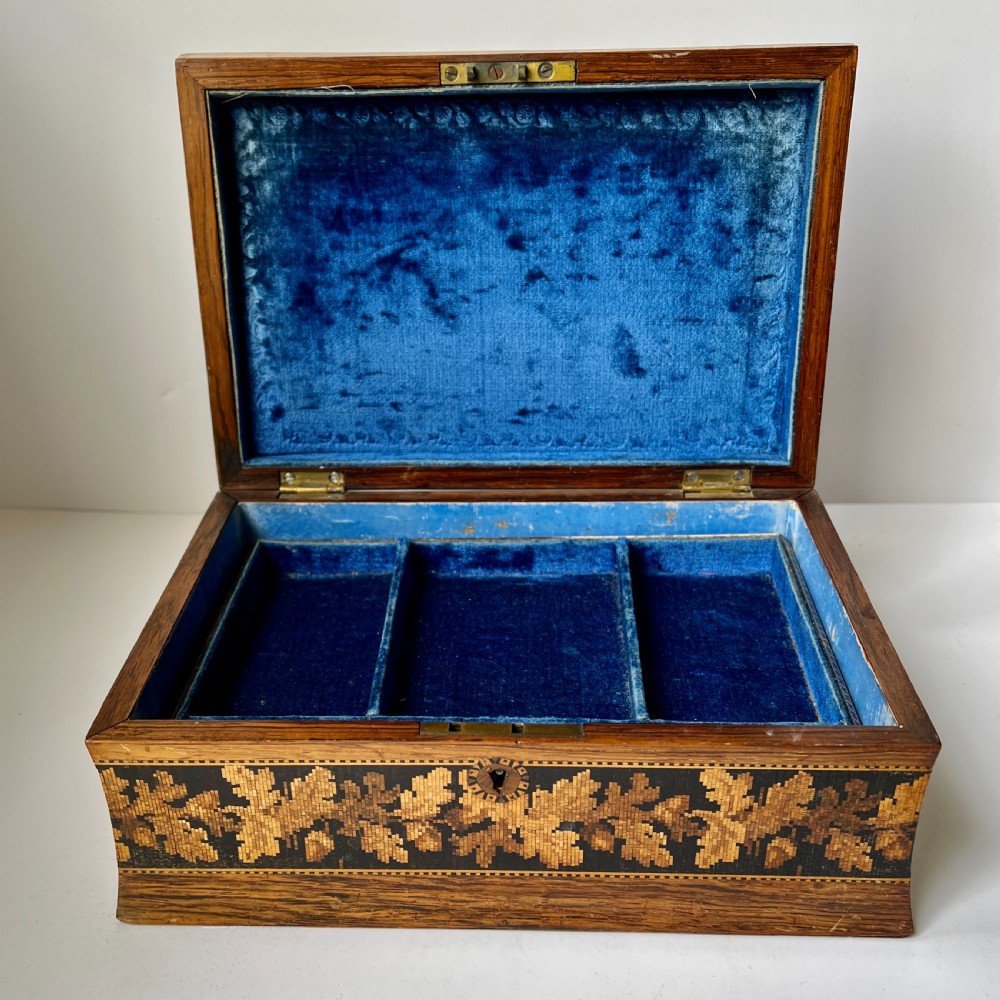 A rectangular Victorian Tunbridge ware wooden box featuring flared concave sides, a hinged lid decorated with an inlaid landscape, and leaf mosaic borders. View III