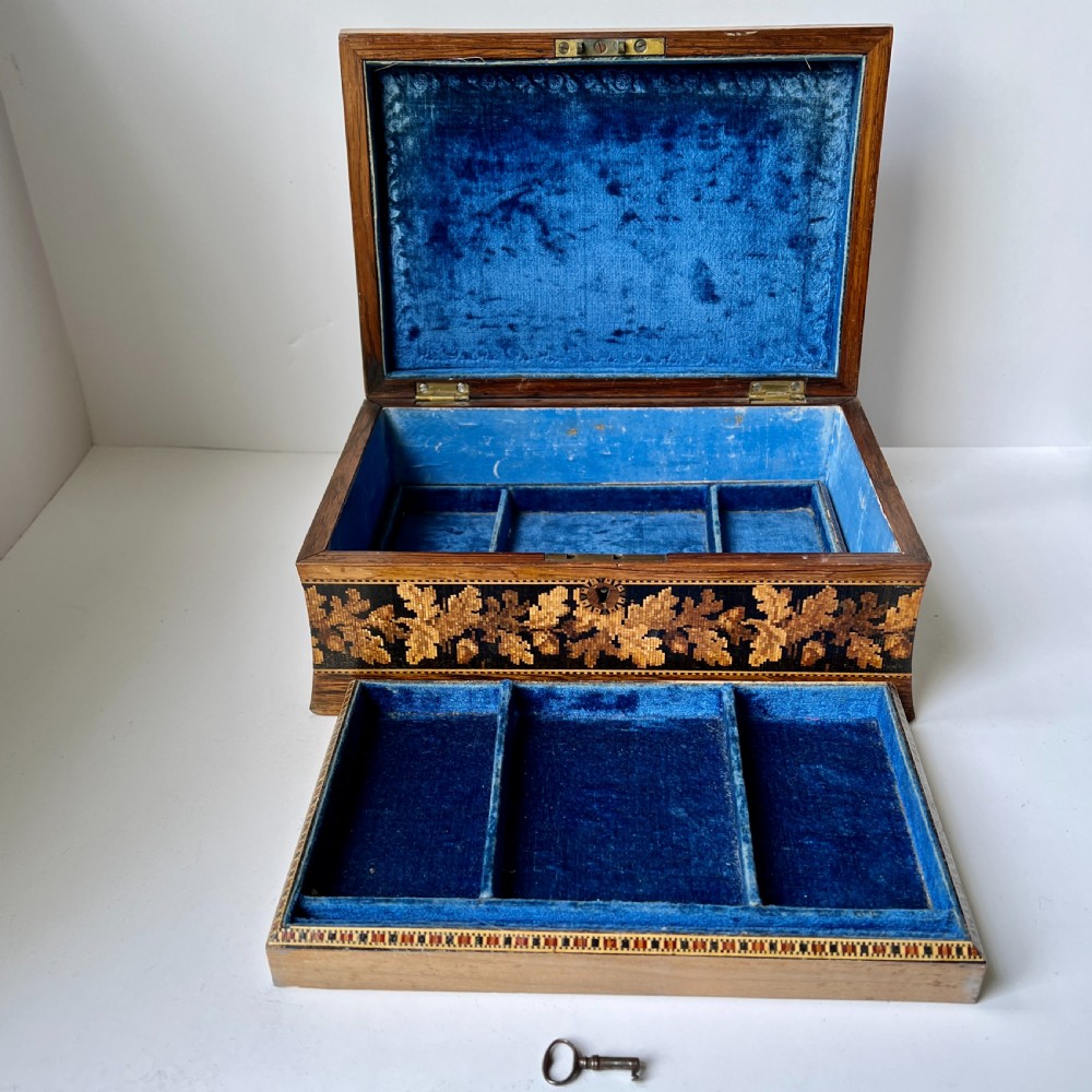 A rectangular Victorian Tunbridge ware wooden box featuring flared concave sides, a hinged lid decorated with an inlaid landscape, and leaf mosaic borders. View V