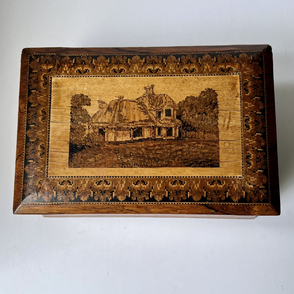 A rectangular Victorian Tunbridge ware wooden box featuring flared concave sides, a hinged lid decorated with an inlaid landscape, and leaf mosaic borders. View VI