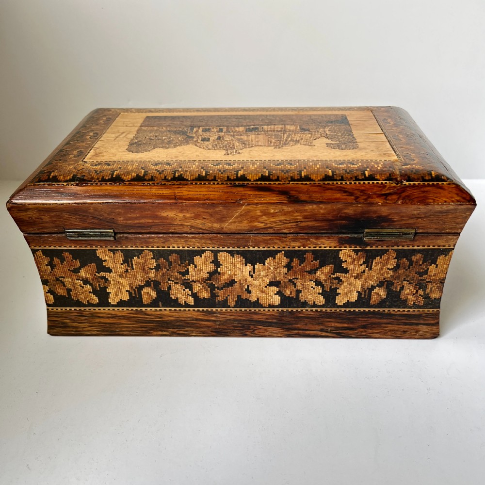 A rectangular Victorian Tunbridge ware wooden box featuring flared concave sides, a hinged lid decorated with an inlaid landscape, and leaf mosaic borders. View VII