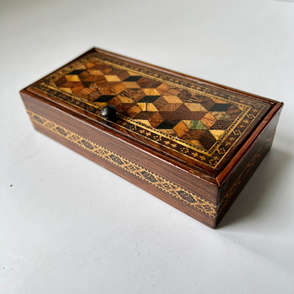 A small rectangular wooden trinket box featuring a geometric tumbling block mosaic lid and an inlaid patterned border. View II