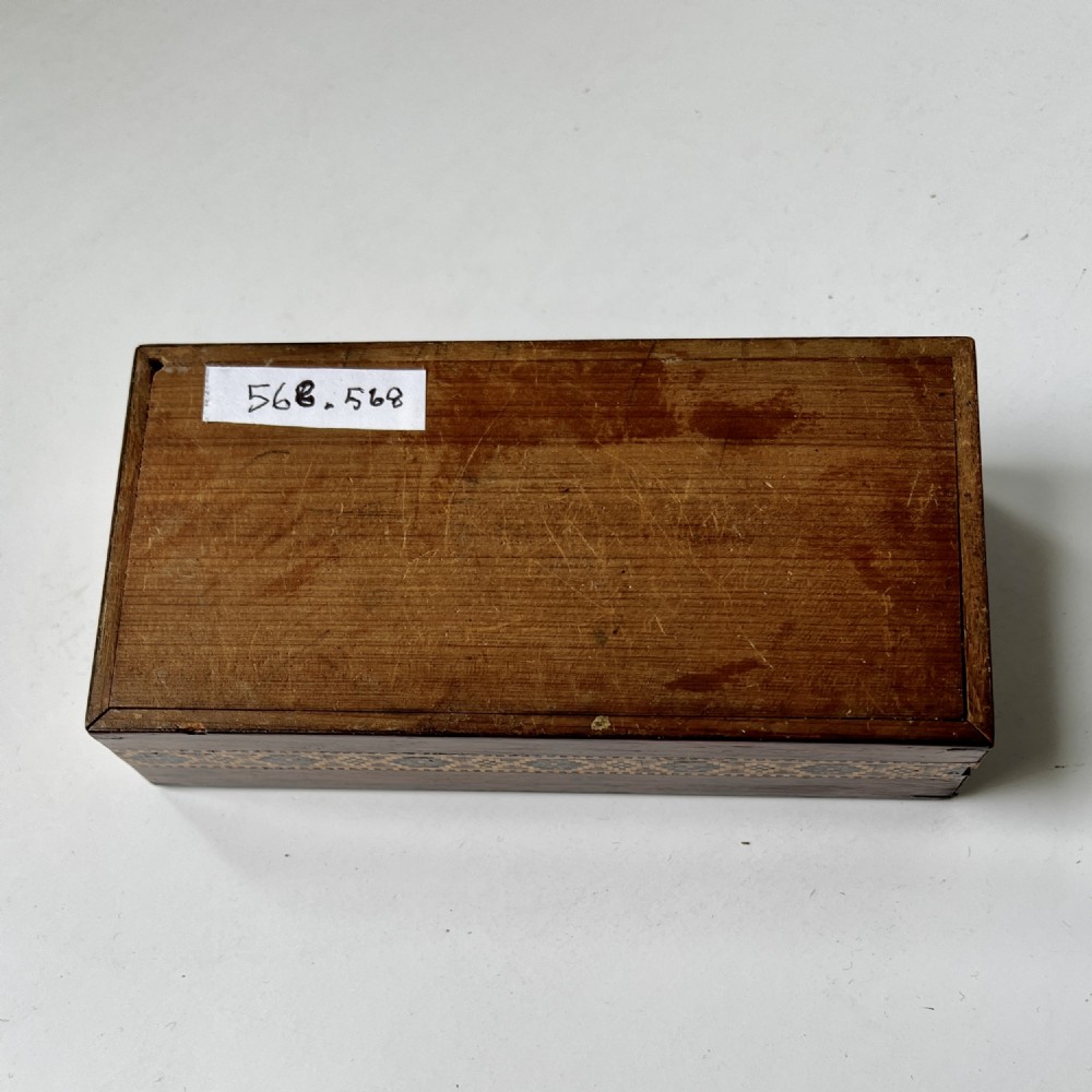 A small rectangular wooden trinket box featuring a geometric tumbling block mosaic lid and an inlaid patterned border. View VI