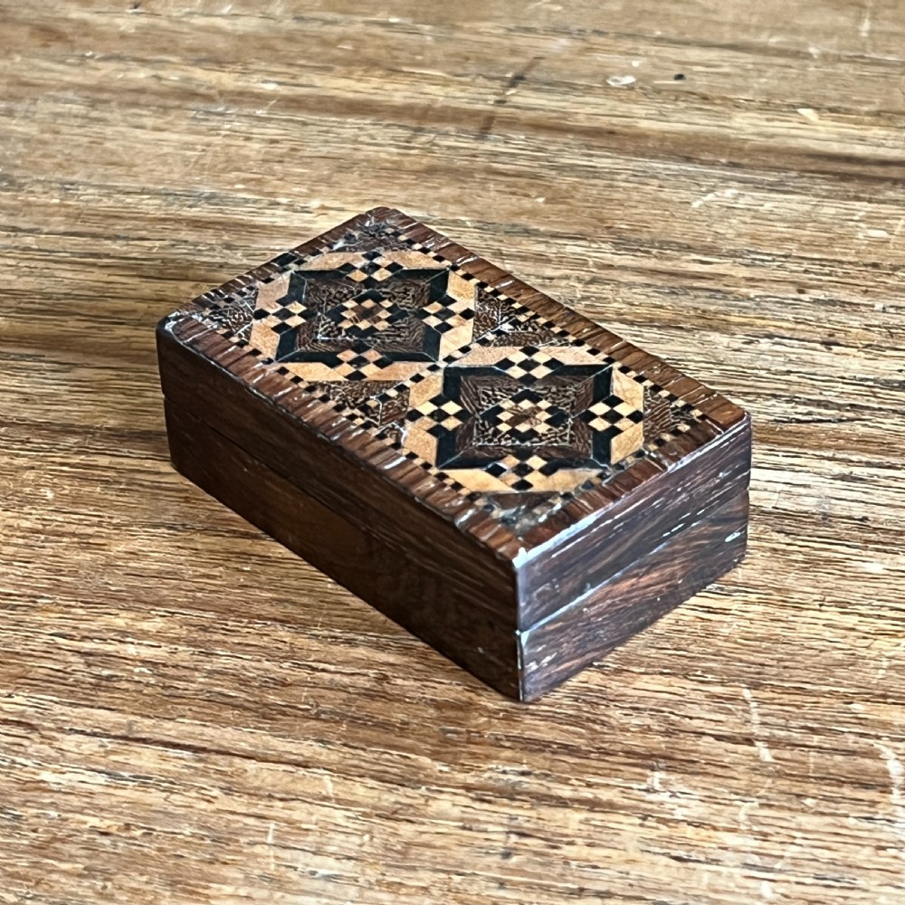 A small rectangular Victorian wooden pin box featuring geometric parquetry inlay in contrasting light and dark woods across the lid.