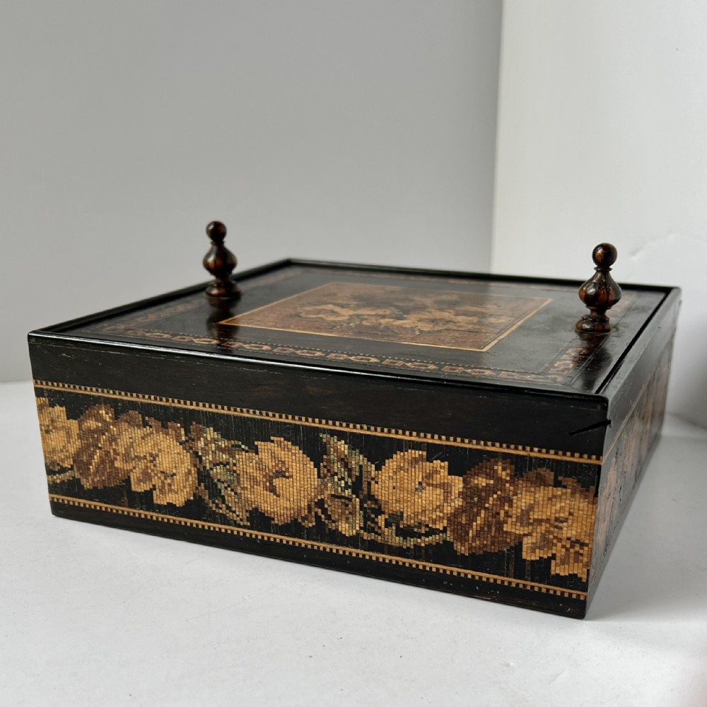 A dark rosewood Tunbridge ware box featuring a micro-mosaic floral border around the sides and turned wooden finials on the top lid.