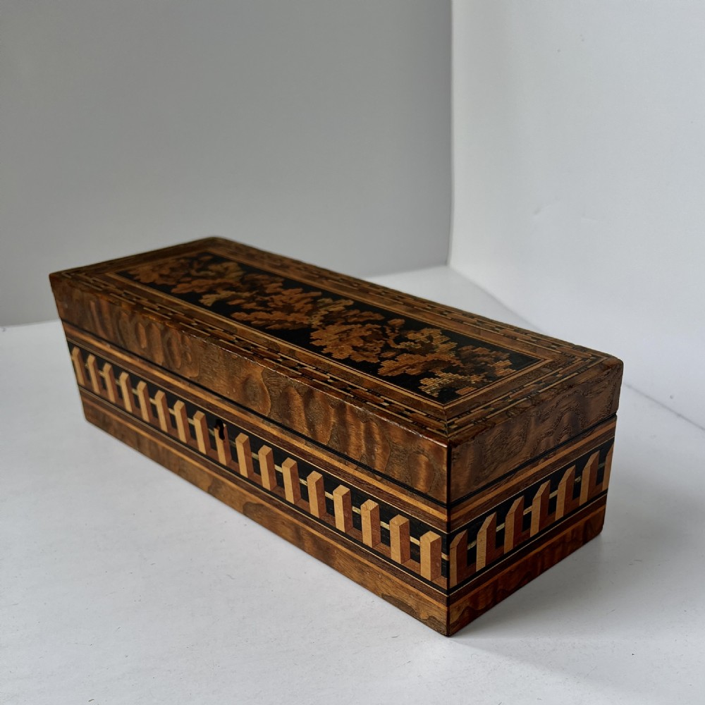 A rectangular Victorian Tunbridge ware wooden glove box with a floral mosaic top panel and a geometric inlaid border.