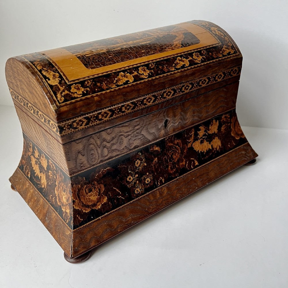 A Victorian Tunbridge ware domed wooden tea caddy with floral and geometric mosaic marquetry inlays resting on small feet.
