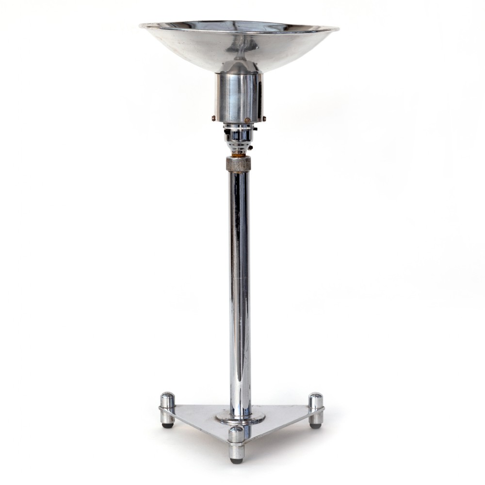 An Art Deco chromium-plated table uplighter featuring a dish-shaped reflector shade, a central cylindrical stem, and a triangular base with raised spherical feet.