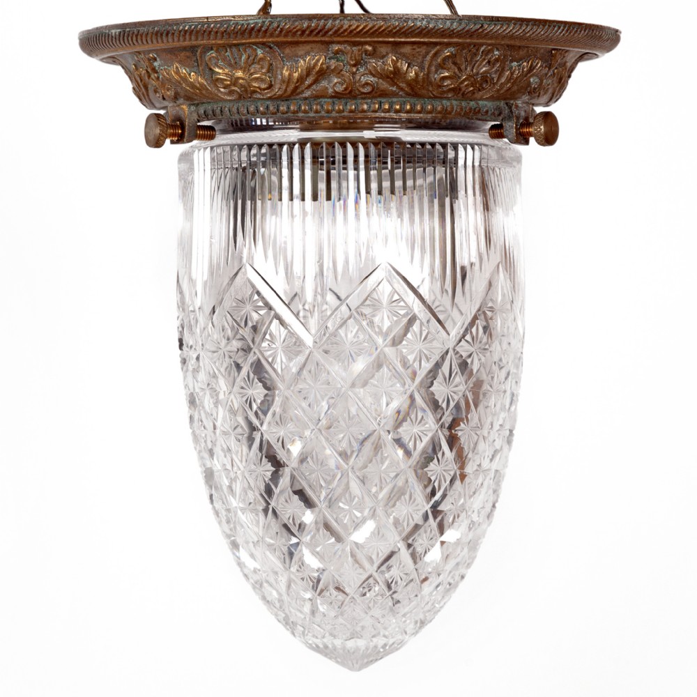 An Edwardian ceiling pendant featuring a pointed cut glass shade held by a decorative cast brass gallery with thumbscrews.