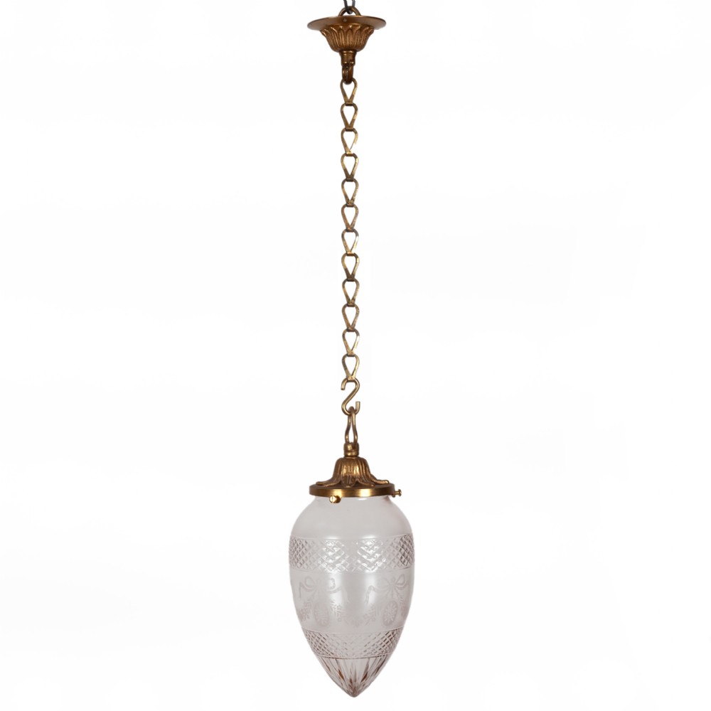 An Edwardian pendant light with a brass ceiling rose, linked brass chain, and an acorn-shaped glass shade featuring frosted panels and cut glass diamond motifs.