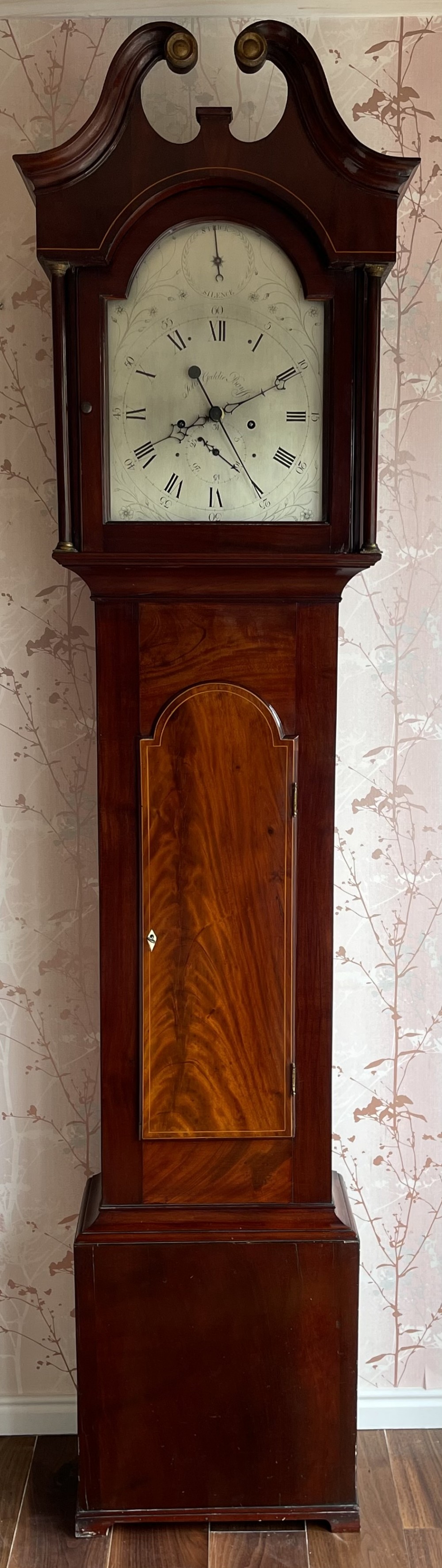 A Georgian Scottish mahogany longcase clock featuring a swan-neck pediment, an arched dial with Roman numerals, and a flame mahogany trunk door.