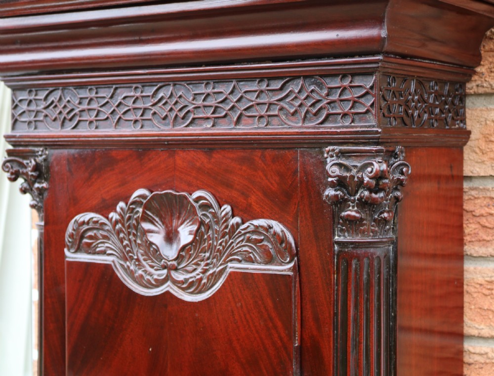 An 18th-century Chippendale flame mahogany longcase clock featuring a swan-neck pediment, reeded columns, and a painted arch dial face. View IV