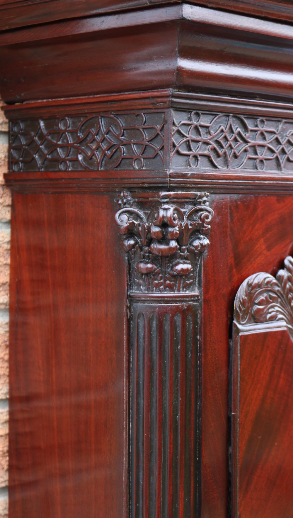 An 18th-century Chippendale flame mahogany longcase clock featuring a swan-neck pediment, reeded columns, and a painted arch dial face. View X