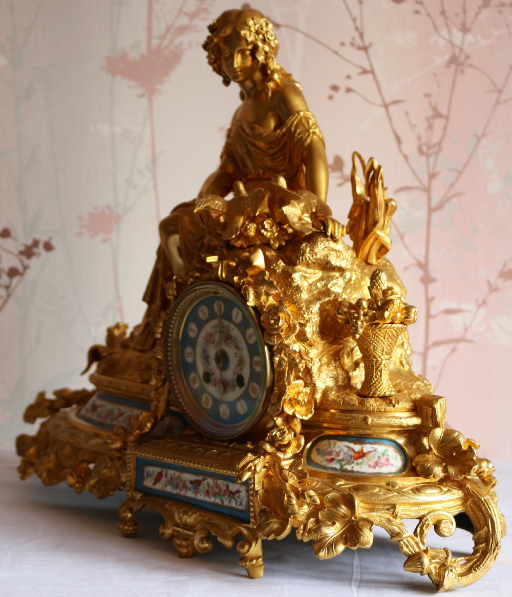 An ornate 19th-century French gilt bronze ormolu mantel clock topped with a classic draped female figure, featuring turquoise porcelain panels painted with flowers and birds. View II