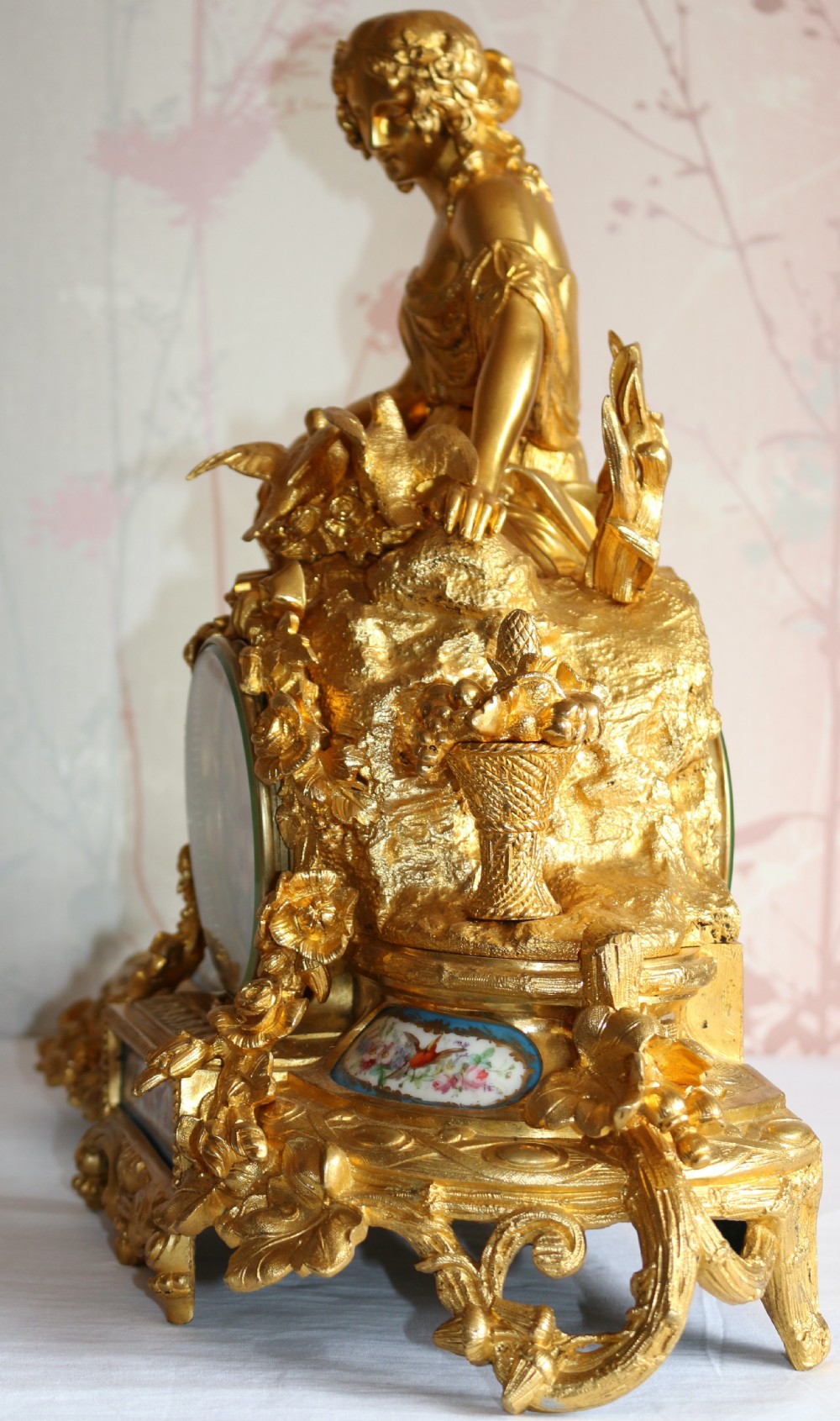 An ornate 19th-century French gilt bronze ormolu mantel clock topped with a classic draped female figure, featuring turquoise porcelain panels painted with flowers and birds. View IV