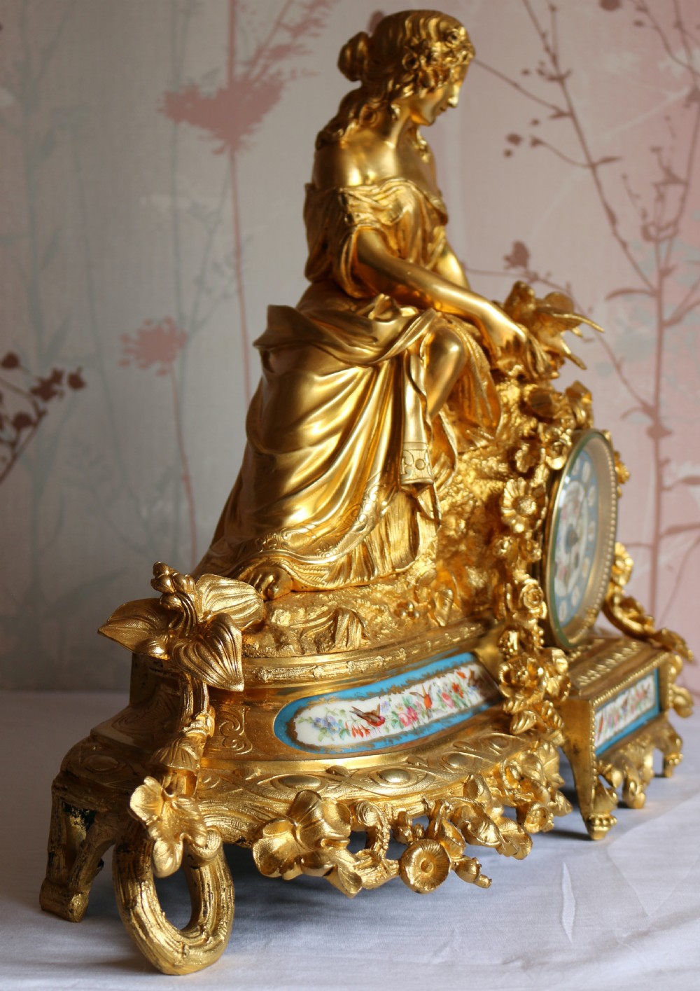 An ornate 19th-century French gilt bronze ormolu mantel clock topped with a classic draped female figure, featuring turquoise porcelain panels painted with flowers and birds. View VII