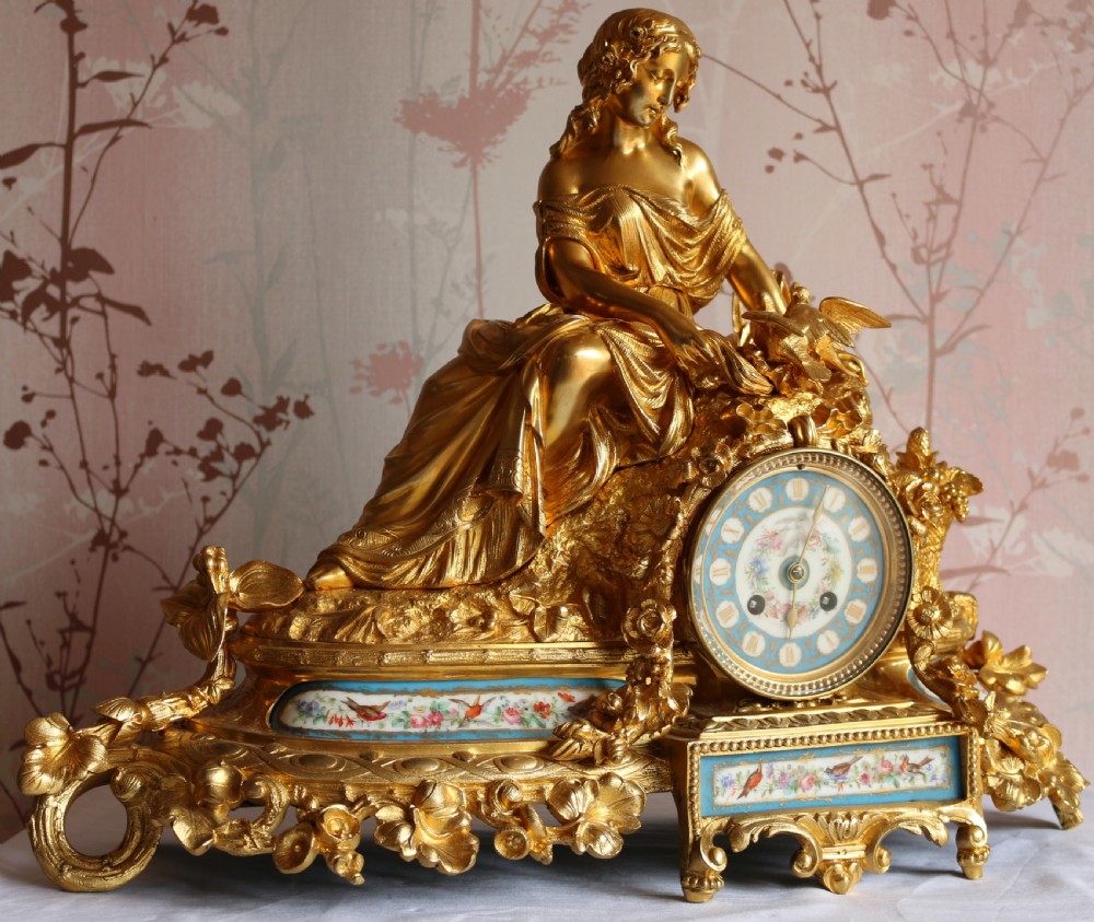 An ornate 19th-century French gilt bronze ormolu mantel clock topped with a classic draped female figure, featuring turquoise porcelain panels painted with flowers and birds. View VIII