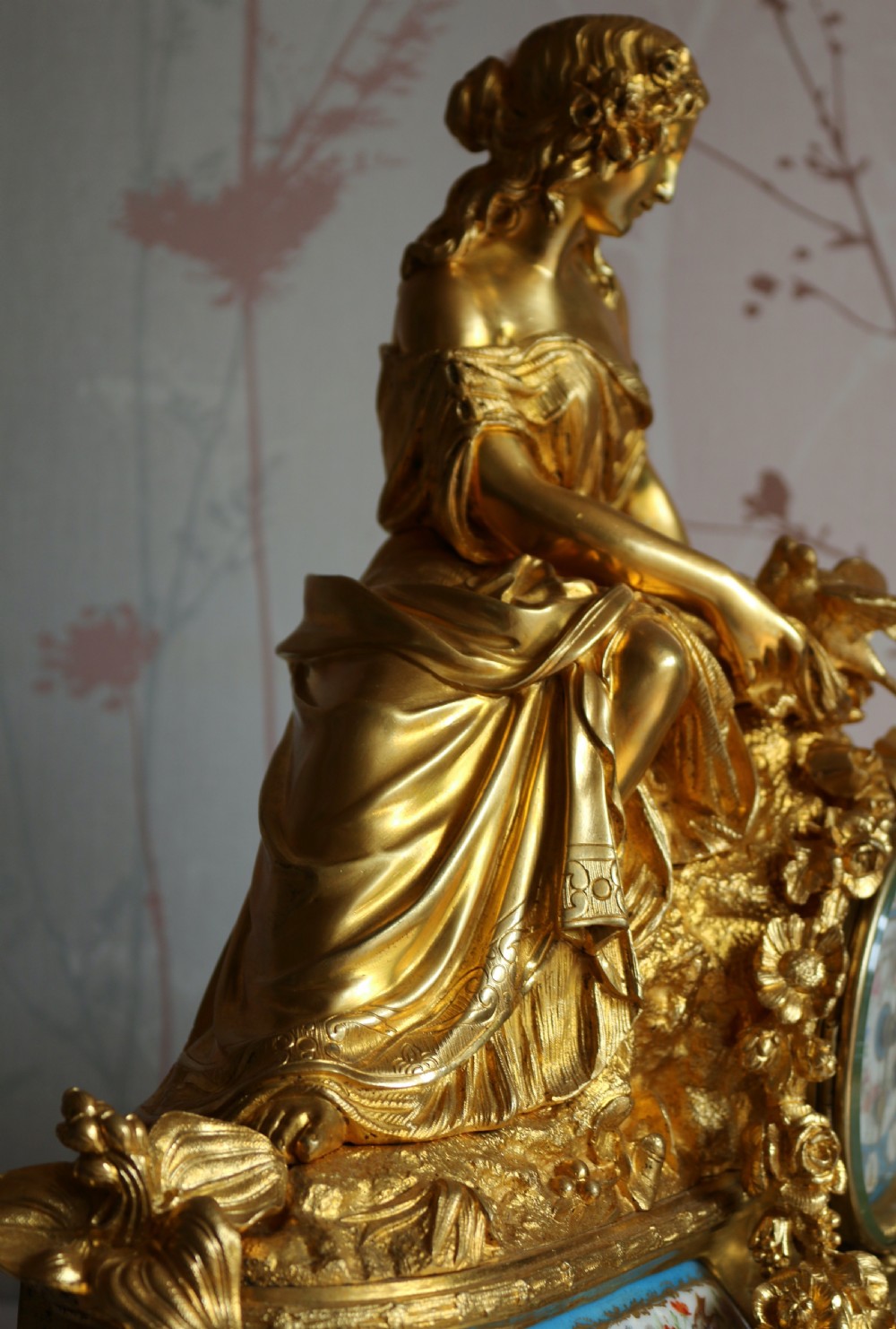 An ornate 19th-century French gilt bronze ormolu mantel clock topped with a classic draped female figure, featuring turquoise porcelain panels painted with flowers and birds. View IX