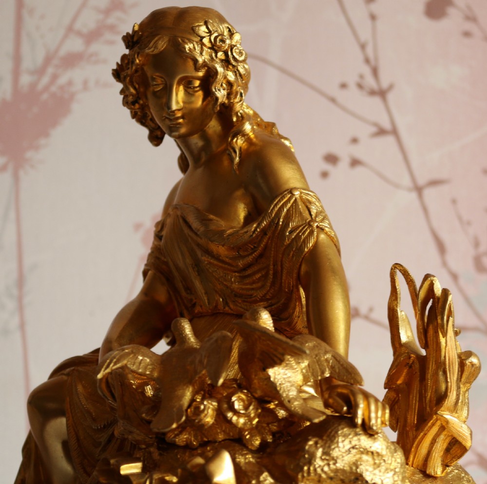 An ornate 19th-century French gilt bronze ormolu mantel clock topped with a classic draped female figure, featuring turquoise porcelain panels painted with flowers and birds. View X