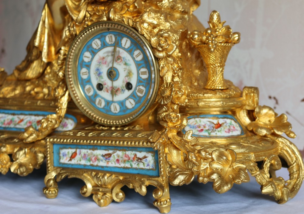 An ornate 19th-century French gilt bronze ormolu mantel clock topped with a classic draped female figure, featuring turquoise porcelain panels painted with flowers and birds. View XIII