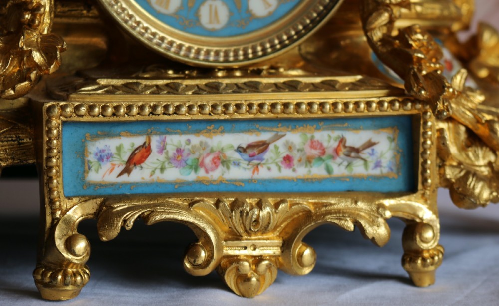 An ornate 19th-century French gilt bronze ormolu mantel clock topped with a classic draped female figure, featuring turquoise porcelain panels painted with flowers and birds. View XV