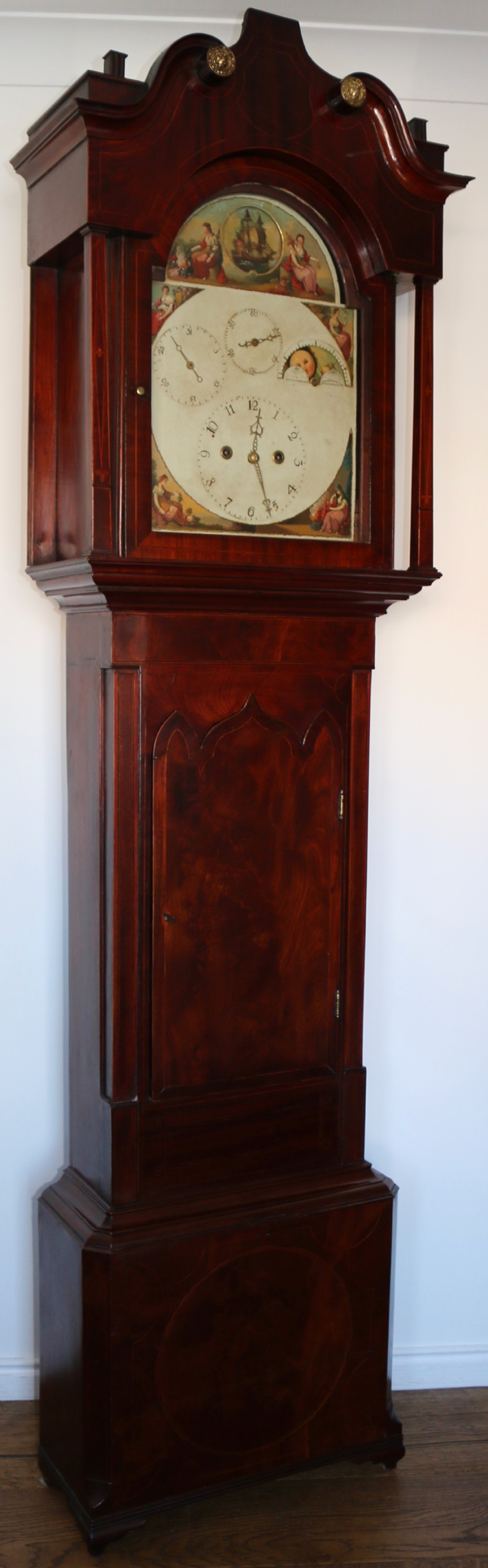 A Georgian mahogany longcase clock featuring a swan-neck pediment, a hand-painted dial with auxiliary subdials, and a rocking ship automaton in the arch.