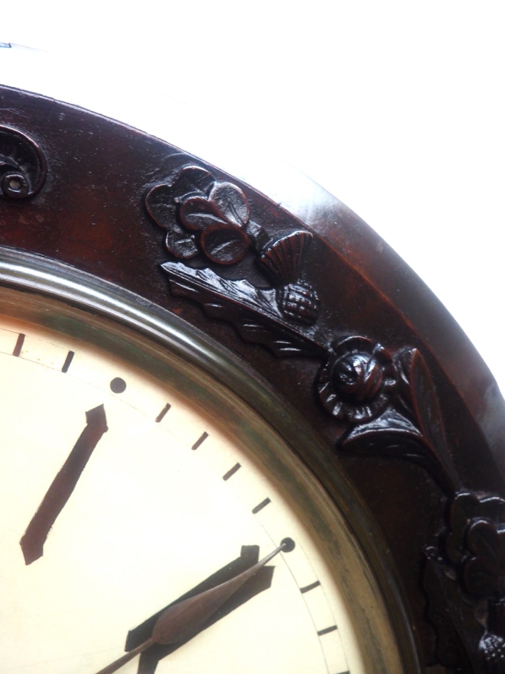 An antique Victorian carved dark mahogany wall clock featuring an off-white dial with Roman numerals marked Berry Cardiff, framed by thistle and vine carvings. View IV