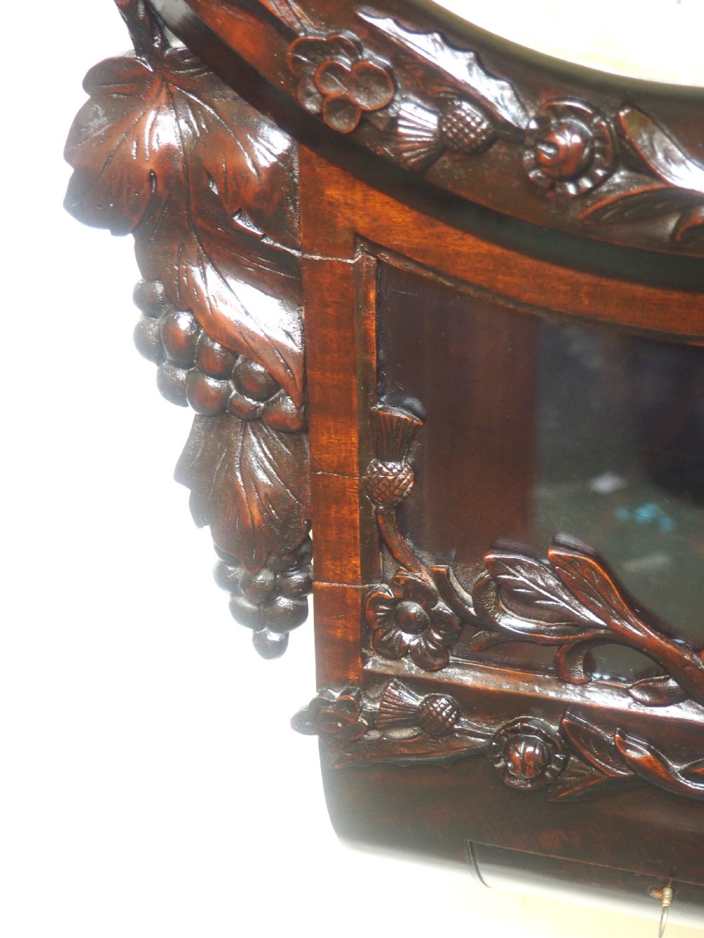 An antique Victorian carved dark mahogany wall clock featuring an off-white dial with Roman numerals marked Berry Cardiff, framed by thistle and vine carvings. View VII
