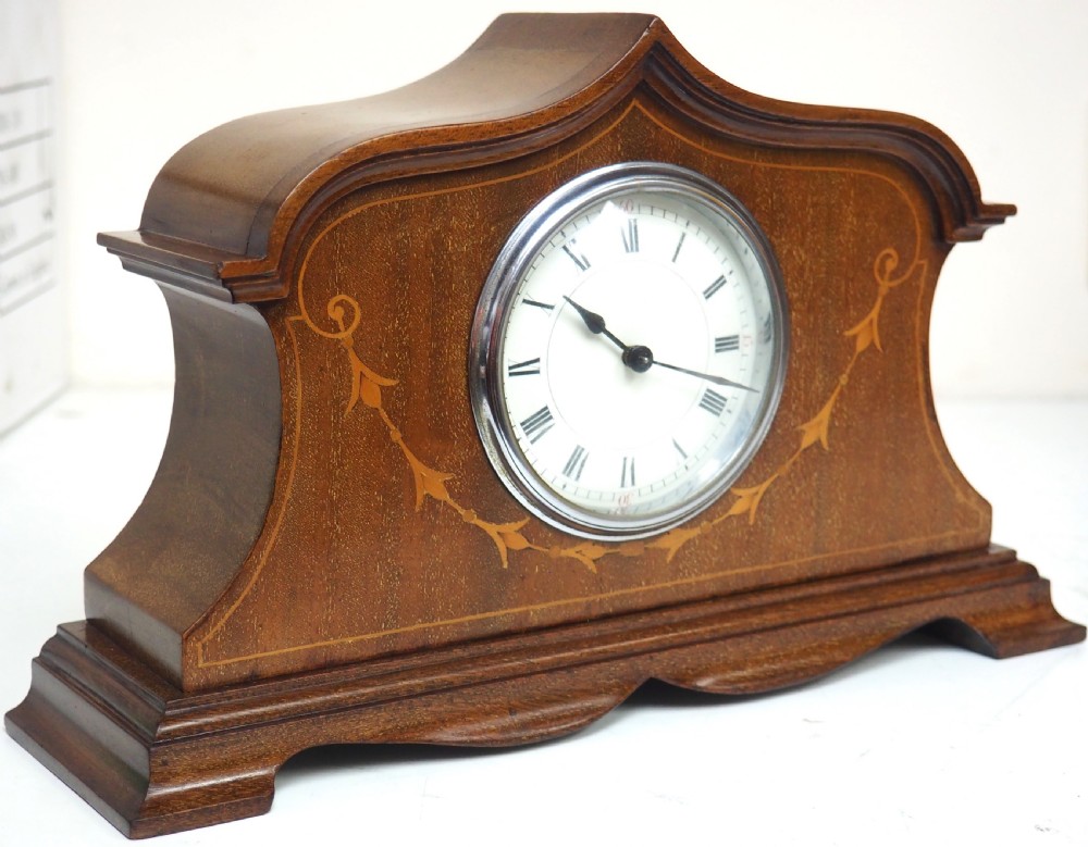 An Edwardian mahogany mantel clock featuring a stepped tulip-top case, floral marquetry inlay, and a white circular dial with Roman numerals. View V