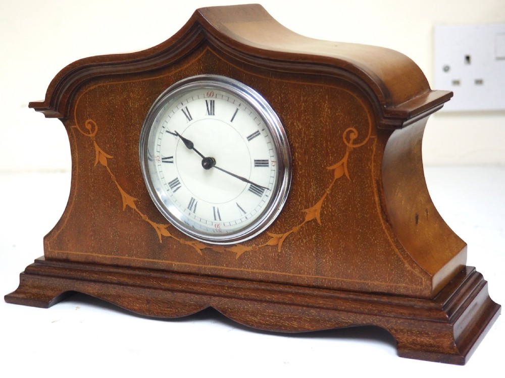 An Edwardian mahogany mantel clock featuring a stepped tulip-top case, floral marquetry inlay, and a white circular dial with Roman numerals. View VI