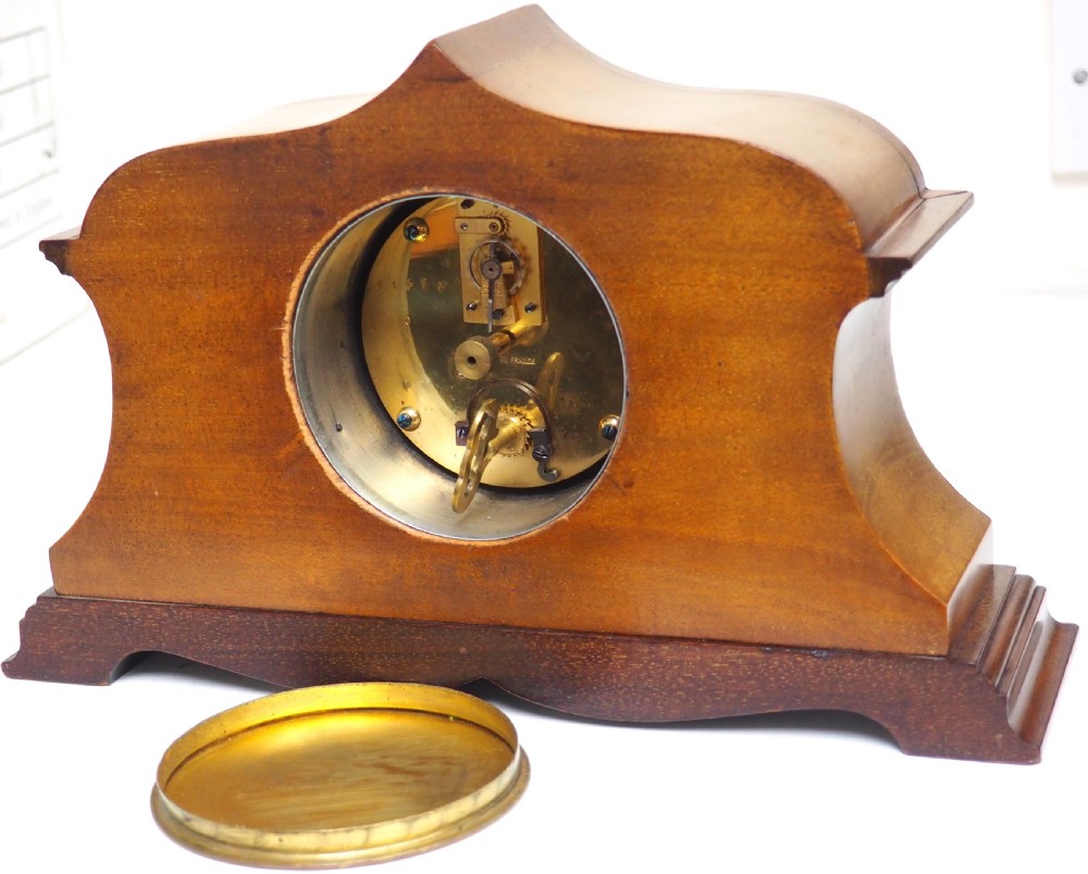 An Edwardian mahogany mantel clock featuring a stepped tulip-top case, floral marquetry inlay, and a white circular dial with Roman numerals. View X