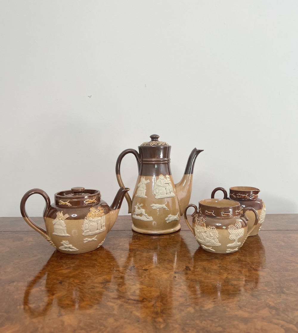 A four-piece two-tone brown glazed stoneware tea and coffee service decorated with white sprigged relief hunting scenes.