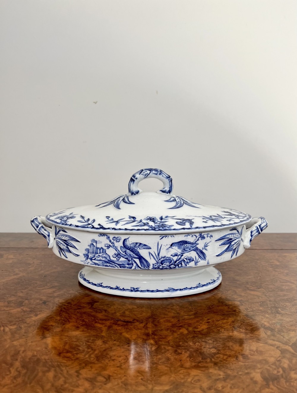 An oval Victorian blue and white transferware ceramic soup tureen with twin handles and a lidded top decorated with bird and foliage motifs.