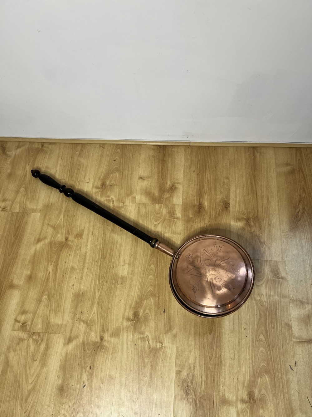An antique George III copper warming pan featuring a chased circular hinged lid and a dark turned wooden handle.