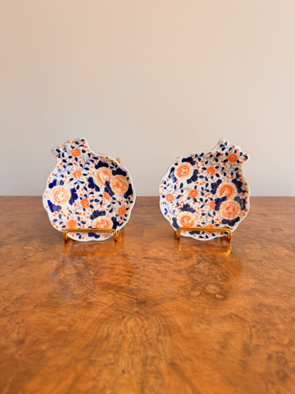 A pair of Japanese Imari porcelain dishes featuring a shell-like shape decorated with floral patterns in cobalt blue and iron red.