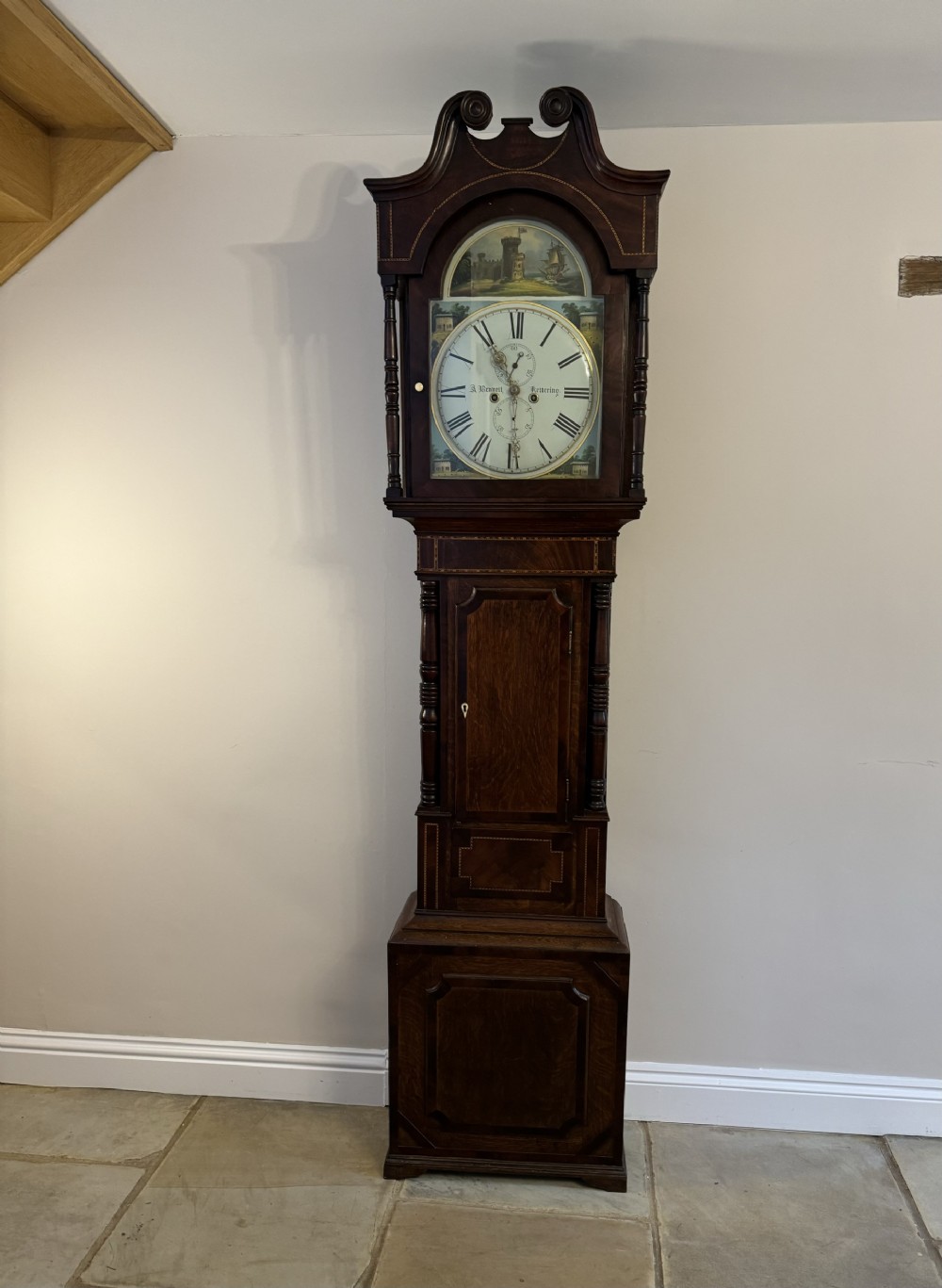 A George III mahogany and oak longcase clock featuring a hand-painted dial, swan-neck pediment, and fluted column details.