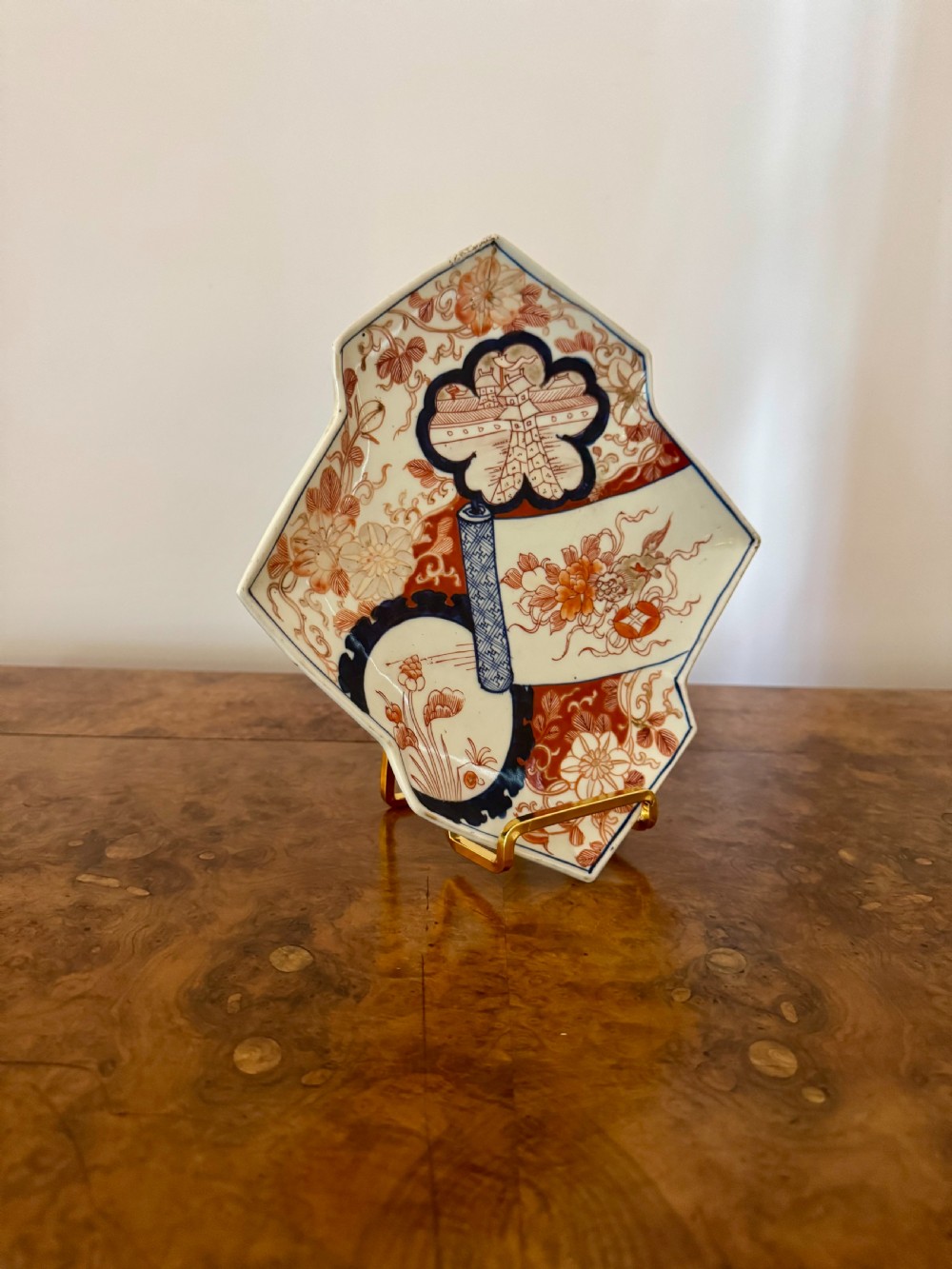 A diamond-shaped Japanese Imari porcelain dish featuring red and blue floral patterns and scroll motifs painted on a white glaze. View II