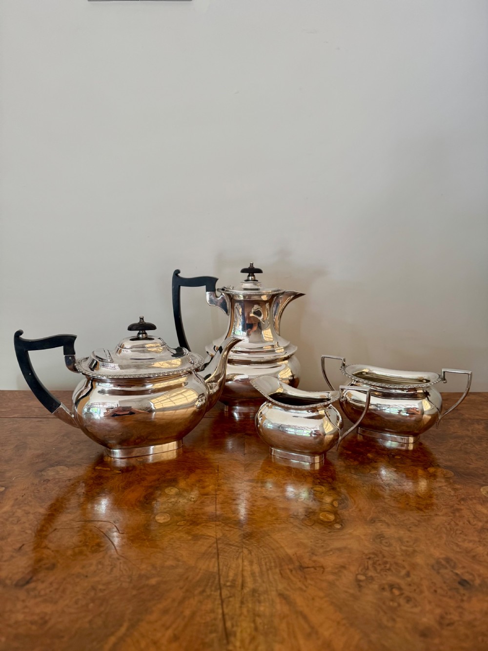 A four-piece Edwardian silver tea set comprising a teapot, coffee pot, cream jug, and sugar bowl with black wooden handles. View II