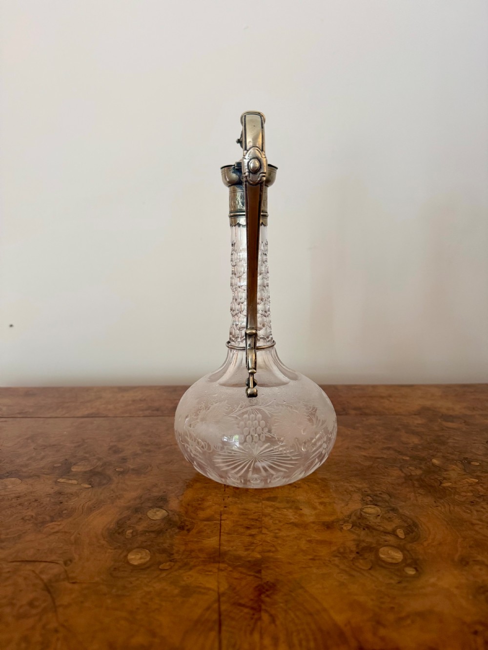 A Victorian clear etched glass claret jug featuring floral vine patterns, a textured glass neck, and a silver-plated collar with a scroll handle and finial lid. View III