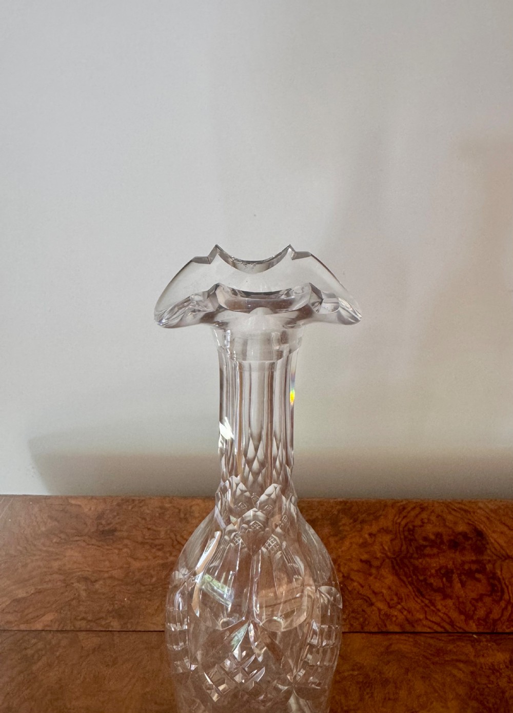 A trio of tall Edwardian clear cut glass decanters featuring geometric faceted stoppers and diamond cut pattern details. View IV