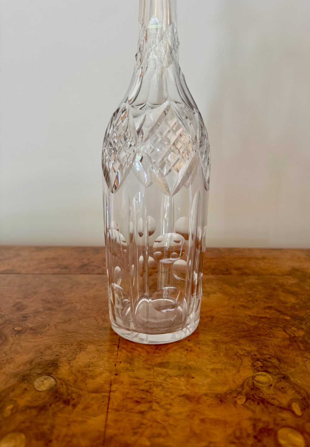 A trio of tall Edwardian clear cut glass decanters featuring geometric faceted stoppers and diamond cut pattern details. View V