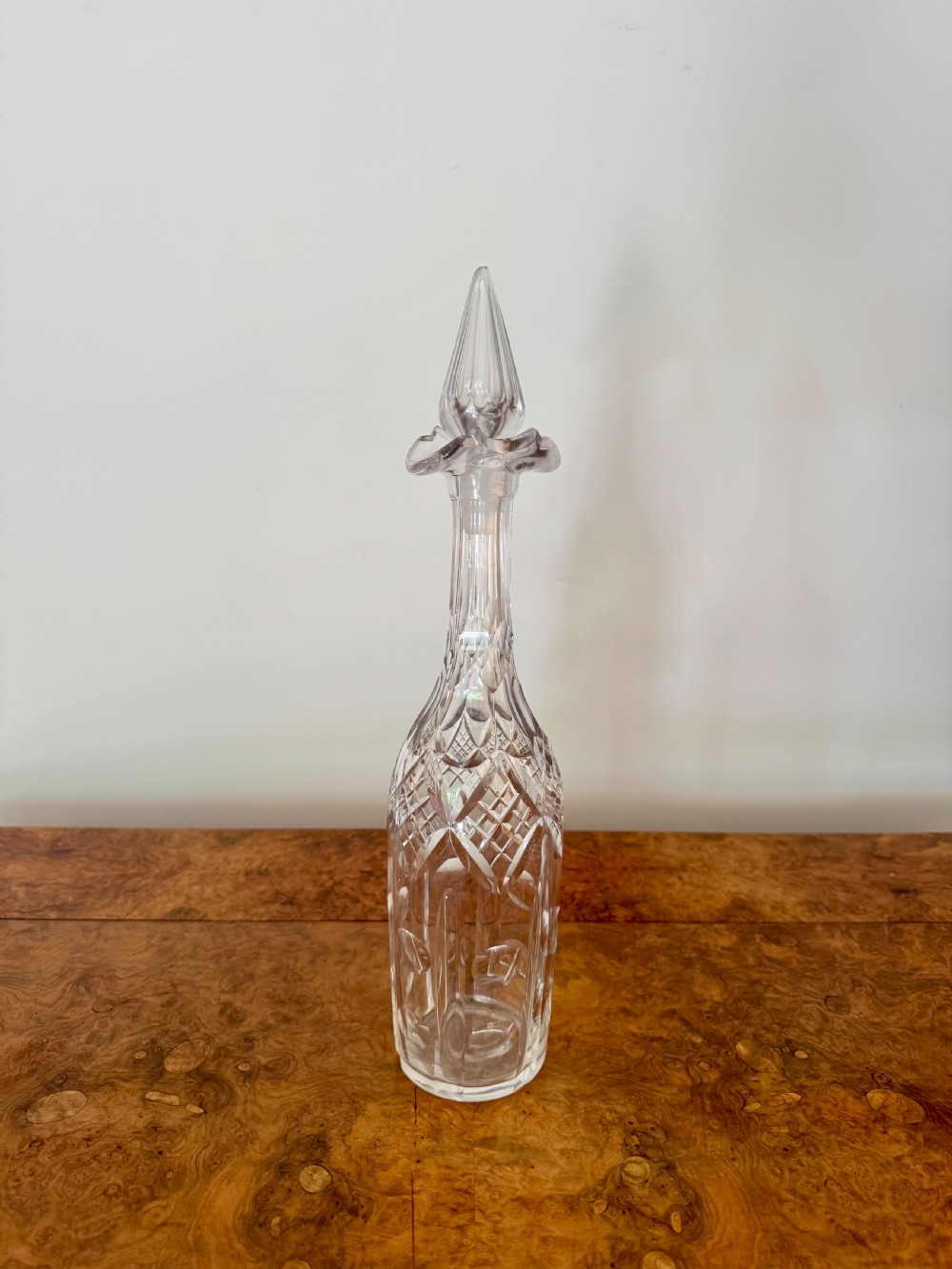A trio of tall Edwardian clear cut glass decanters featuring geometric faceted stoppers and diamond cut pattern details. View VI