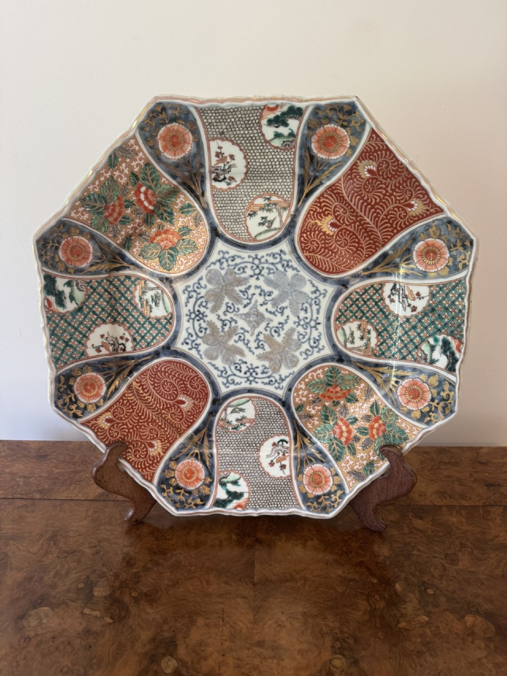 A large 19th-century octagonal Japanese Imari porcelain charger decorated with alternating panels of iron-red floral motifs, cobalt blue lattice patterns, and gilded accents.
