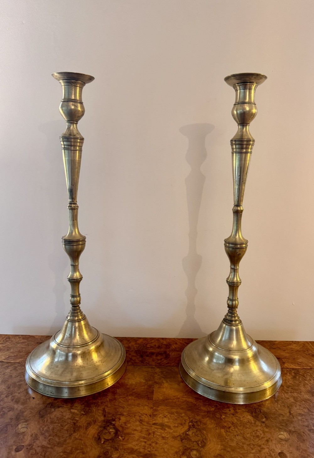 A pair of tall Victorian turned brass candlesticks featuring baluster shafts and wide stepped circular bases.