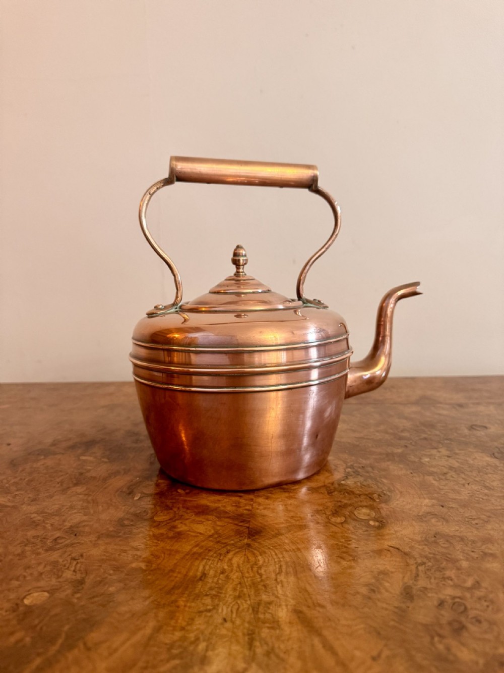 A polished Victorian copper kettle featuring a curved gooseneck spout, stepped lid with turned finial, and a fixed overhead handle.