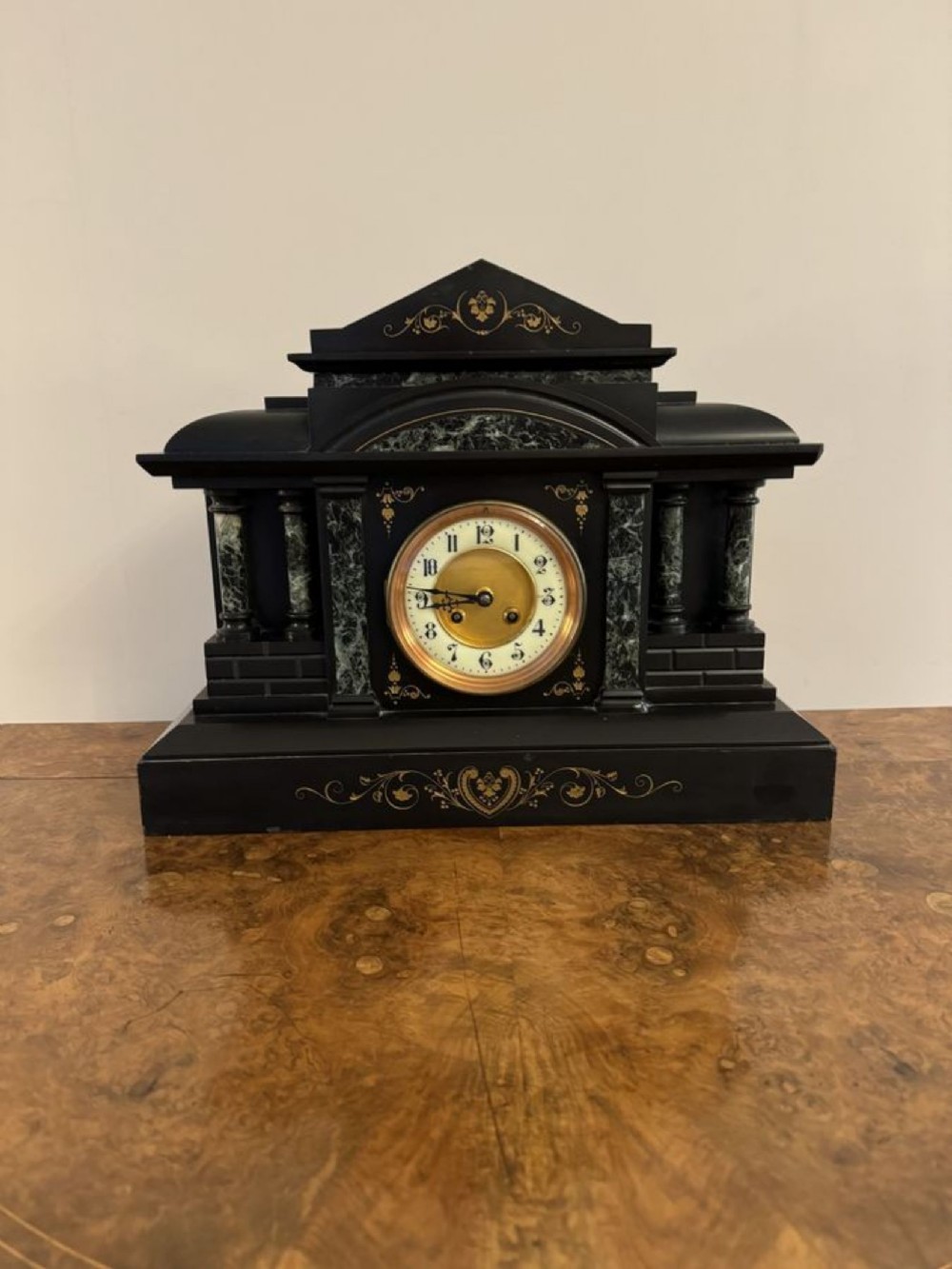 A Victorian architectural black slate mantel clock featuring green marble columns, incised gilded foliate engraving, and an off-white dial with black numerals.