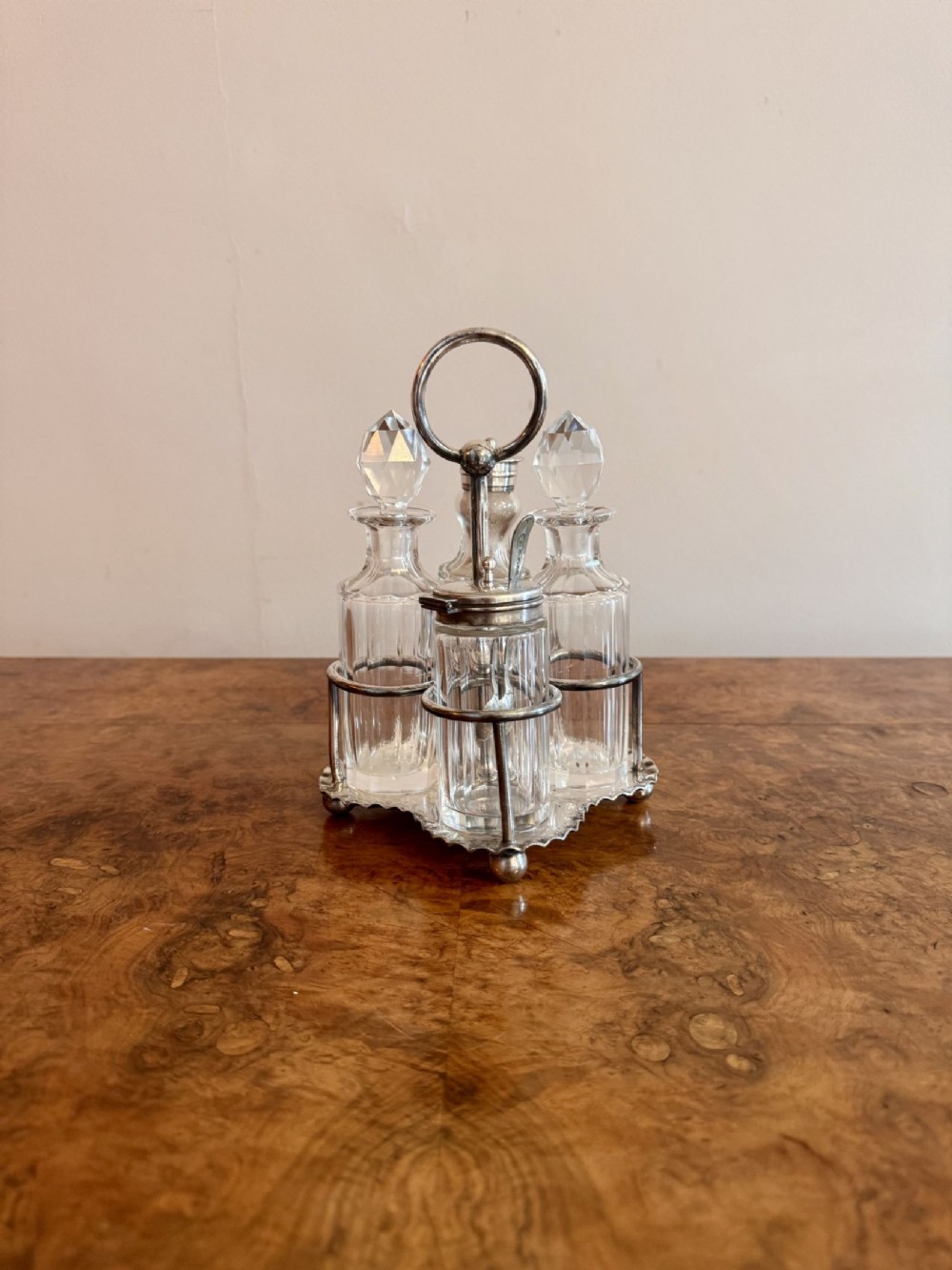 An Edwardian silver-plated cruet stand holding four cut-glass bottles with faceted stoppers.