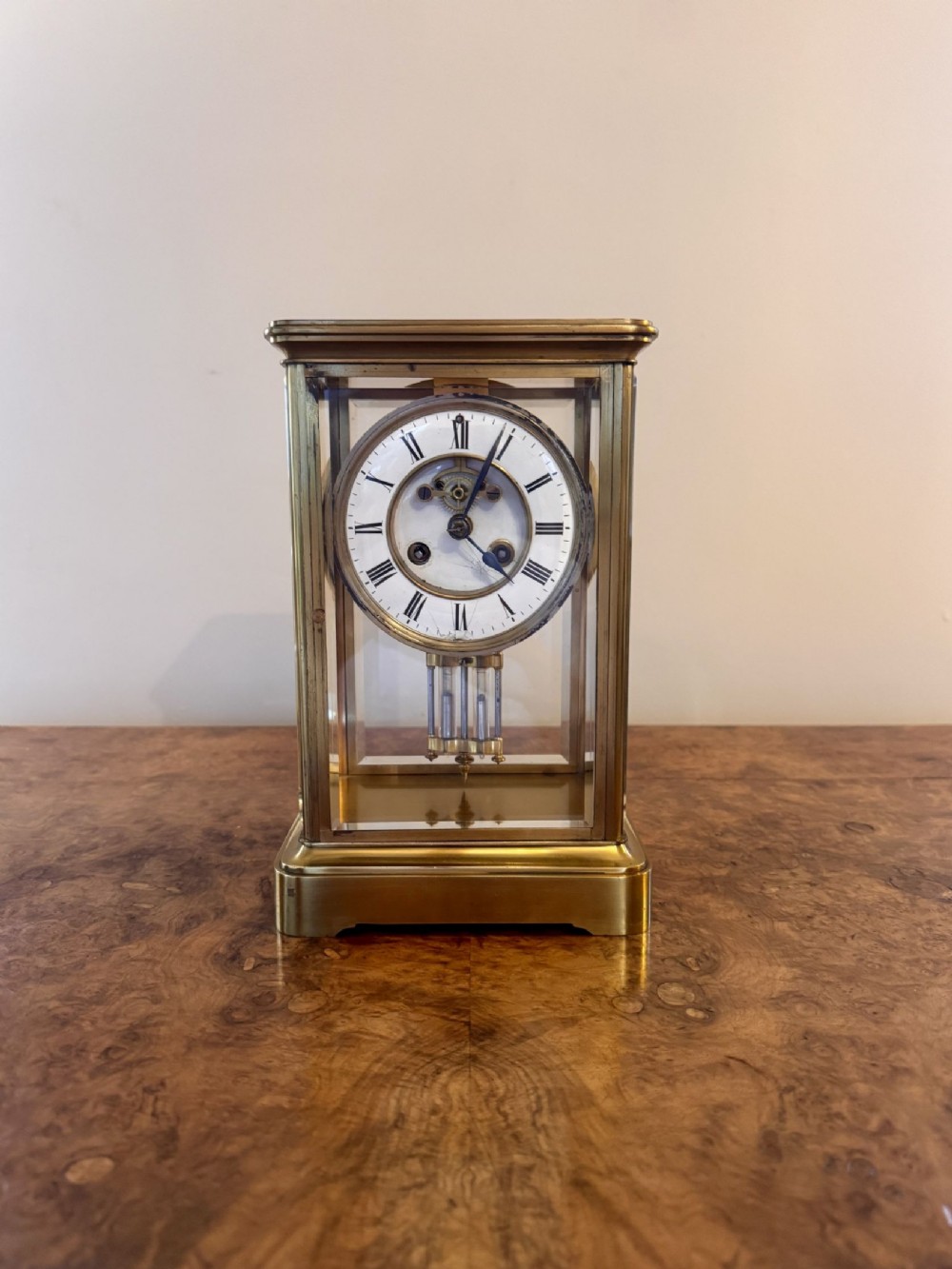 A Victorian brass four-glass mantel clock featuring a white enamel dial with Roman numerals and a visible pendulum mechanism.