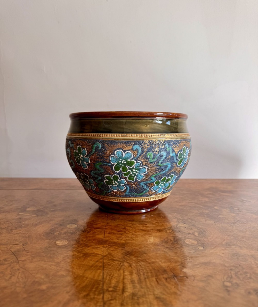 An antique Royal Doulton stoneware jardiniere featuring textured lace-patterned bands, turquoise floral motifs, and a polished brown glazed rim.